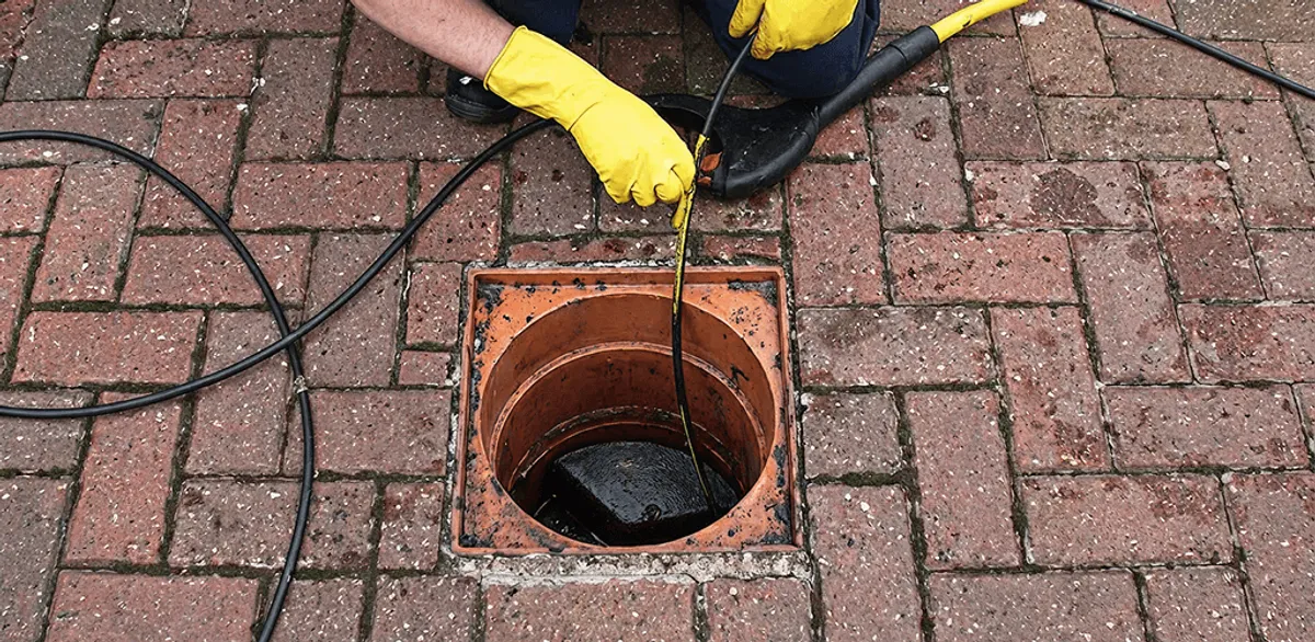 Drain cleaning technician using a drain snake to clear a clogged drain in Saint Louis, MO