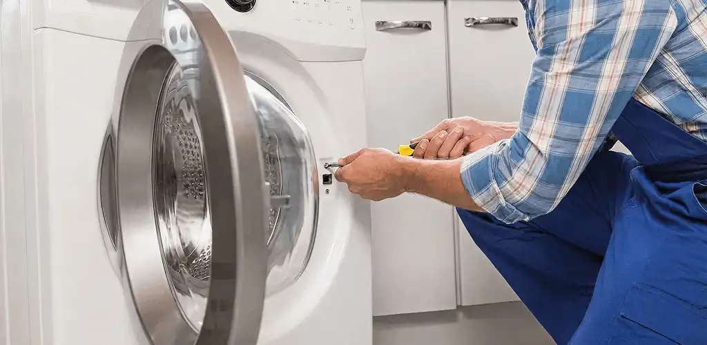 Handyman repairing a clothes dryer and checking electrical connections in Saint Louis, MO