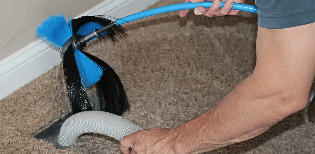 Dryer vent cleaning technician brushing lint from a vent line in Saint Louis, MO