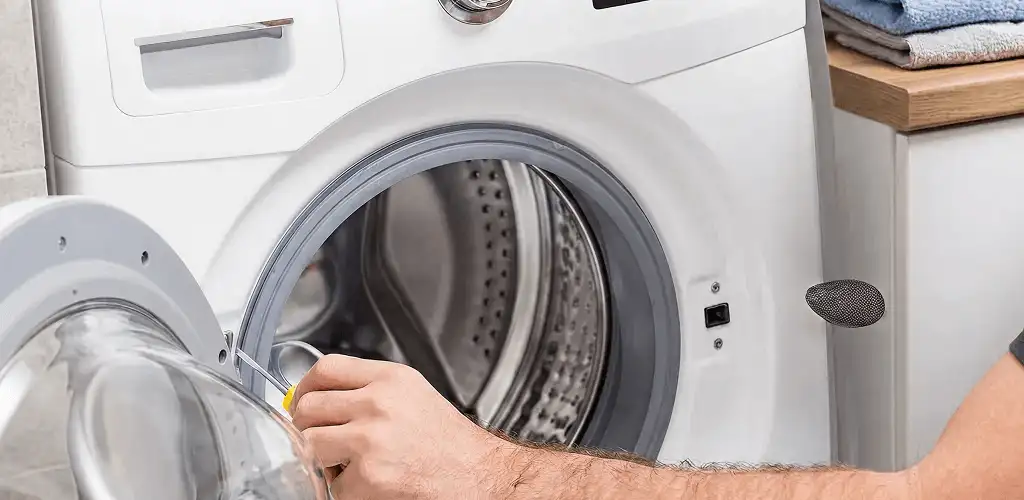 Handyman repairing a front-load washing machine and inspecting the drum in Saint Louis, MO