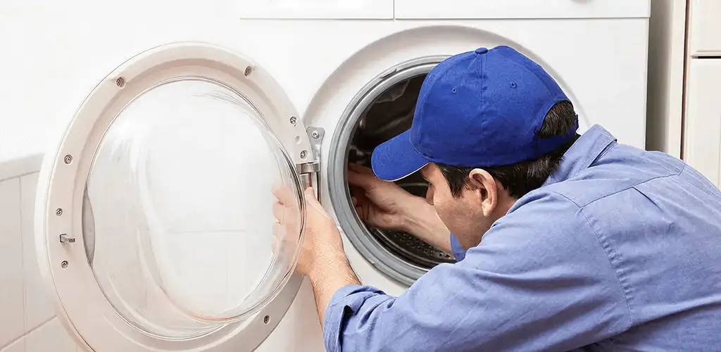 Washing machine repair handyman inspecting a front-load washer drum in Saint Louis, MO