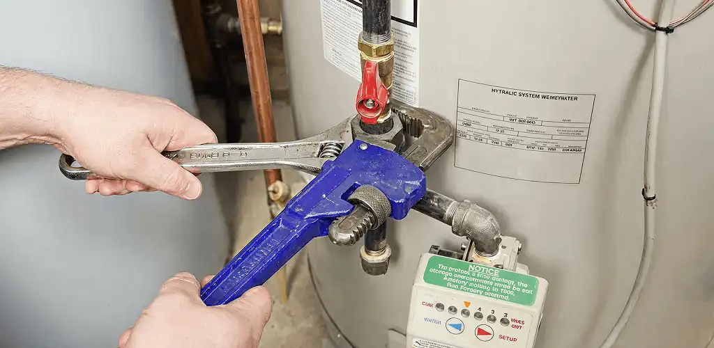 Water heater repair technician tightening the shutoff valve and supply line in Saint Louis, MO